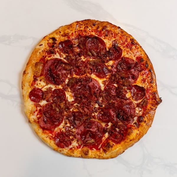 A MONDO PIZZA pepperoni pizza with crumbled sausage and onions on a white marble surface.