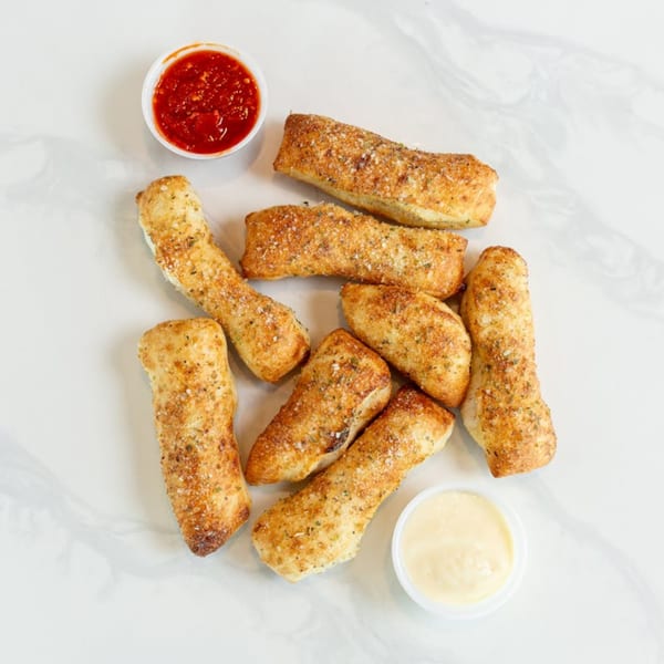 MONDO PIZZA garlic breadsticks with marinara and cheese dipping sauces on a white marble surface.